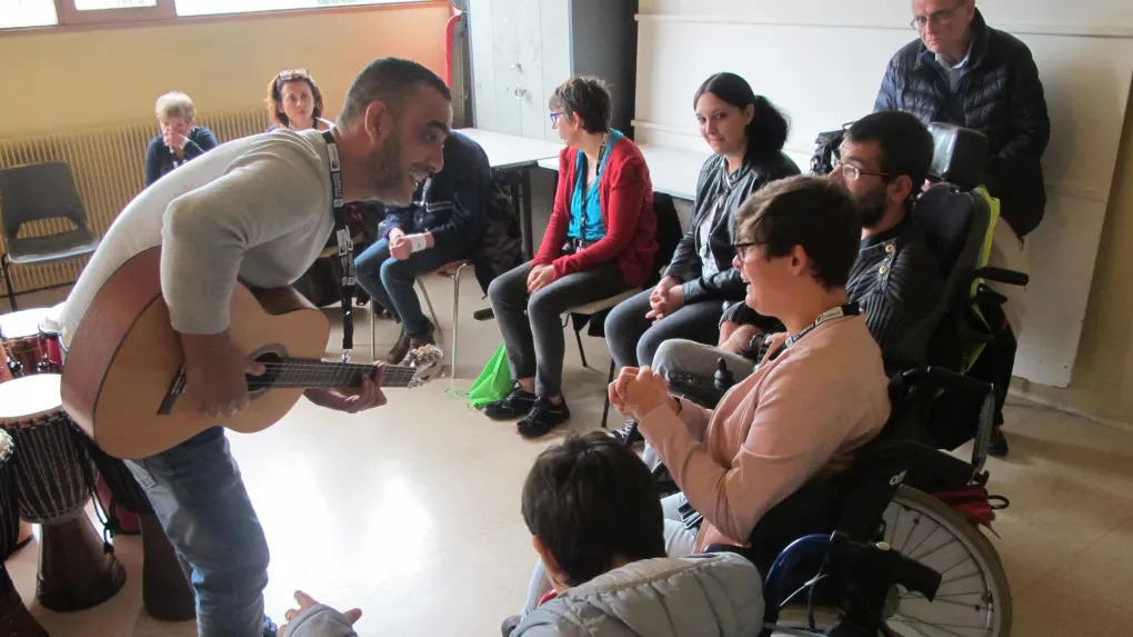 Lahouari Bouregaya joue de la guitare devant un groupe de personnes accompagnées